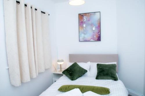 a bedroom with a white bed with green pillows at A luxury 2 bedroom flat in NN1 in Northampton