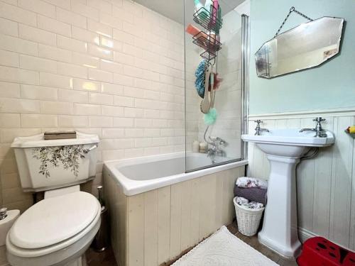 a bathroom with a toilet and a tub and a sink at Wisteria Cottage an authentic and enchanting cottage experience in Aberdare