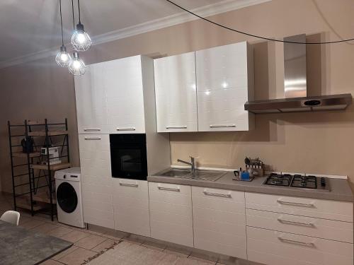 a kitchen with white cabinets and a sink and a dishwasher at La Maison de Marianne in Trepuzzi