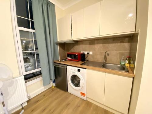 a kitchen with a sink and a washing machine at Private Studio in Central London moments from Oxford St in London