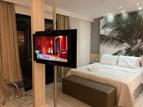 a bedroom with a bed with a television on a pole at Flat Boulevard Side 2104 Altissimo Padrão com Lazer in Salvador