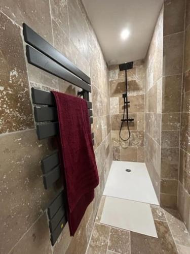 La salle de bains est pourvue d'une serviette rouge accrochée au mur. dans l'établissement Le p'tit Clos, à Lempdes