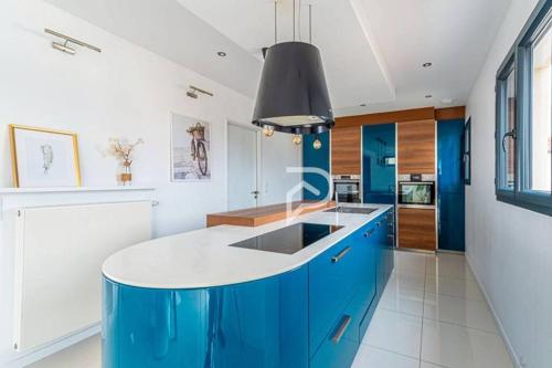 une cuisine avec des armoires bleues et un îlot bleu dans l'établissement Le cocon des 3 frères - Paris CDG/Stade de France, à Goussainville