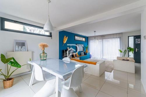 una sala da pranzo con tavolo bianco e parete blu di Le cocon des 3 frères - Paris CDG/Stade de France a Goussainville