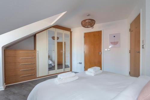 - une chambre avec un grand lit blanc et 2 serviettes dans l'établissement The Balham Loft - NEW Gorgeously appointed with FREE parking and tube close by, à Londres