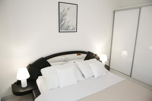 ein Schlafzimmer mit einem schwarzen und weißen Bett mit weißen Kissen in der Unterkunft Apartments Swiss in Vodice