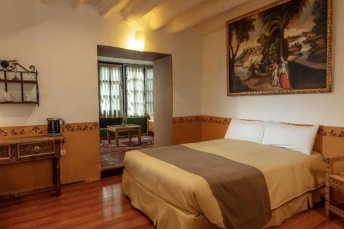 1 dormitorio con 1 cama y una pintura en la pared en Tambo del Arriero Hotel Boutique, en Cusco