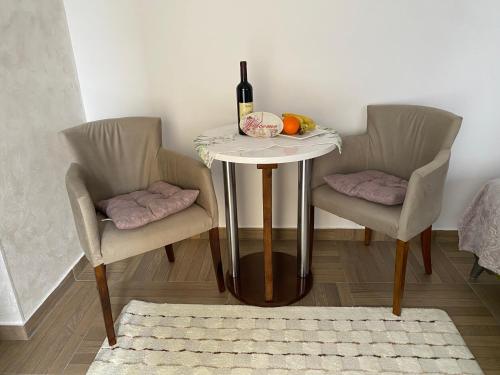 a table with a bottle of wine and two chairs at Apartmani Emily & Jully in Nikšić