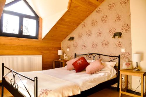 a bedroom with a bed with white sheets and red pillows at Cabana Stana Tarle in Sinaia