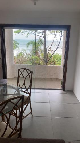 a room with a glass table and a view of the ocean at Casa beira do mar in Florianópolis