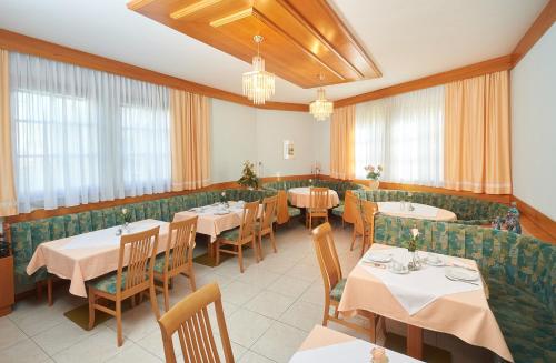 ein Restaurant mit Tischen, Stühlen und Fenstern in der Unterkunft Pension Sprinzl in Schwechat