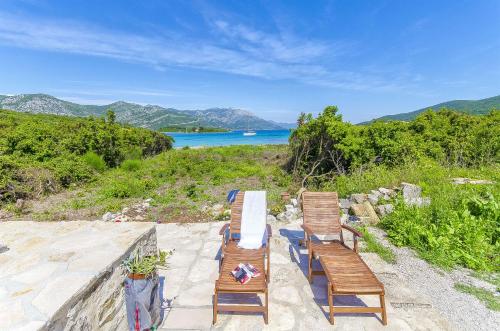 two wooden benches sitting on a patio overlooking a lake at House Vinko in Račišće