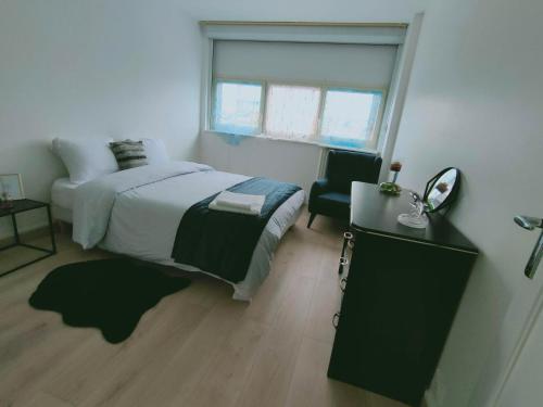 een slaapkamer met een bed, een spiegel en een stoel bij Mon superbe appartement in Argenteuil