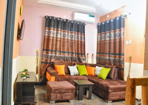 a living room with a brown couch with colorful pillows at CTD Global Integrated in Jos