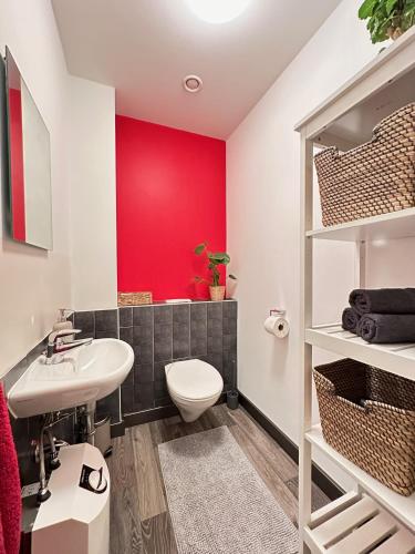 a bathroom with a white toilet and a red wall at Apartment Grindelallee Hamburg in Hamburg