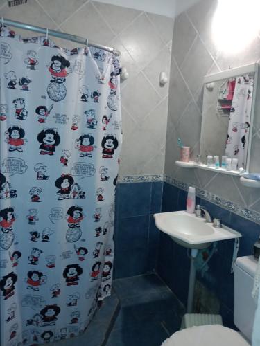 a bathroom with a shower curtain and a sink at Hostal La Palmera in Ezeiza