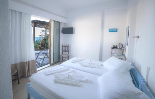 two white beds in a room with a window at Marina Hotel in Agios Kirykos