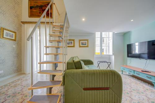 a living room with a green couch and a spiral staircase at Casa Marie, Stay in a Traditional Corner Townhouse in the 3 cities, built in 1881 in Cospicua