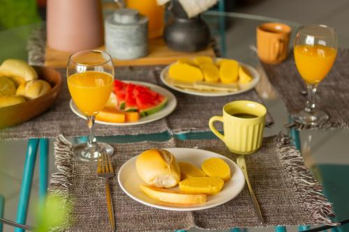 une table avec des assiettes de fruits et des verres de jus d'orange dans l'établissement Refúgio Urbano, à Campina Grande