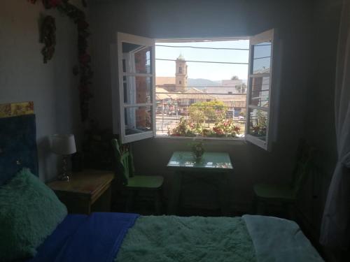 um quarto com uma cama e uma janela com uma torre do relógio em MACONDO apartamento turistico tematico em Zipaquirá