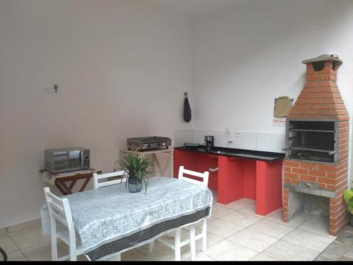 a kitchen with a table and a brick oven at Chalé Maresias in São Sebastião
