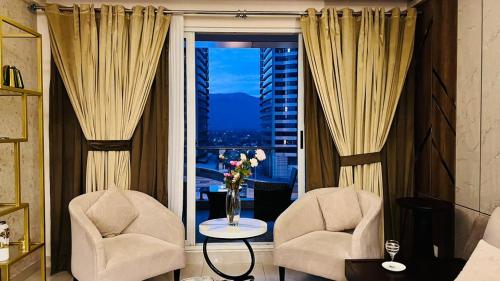 2 stoelen en een tafel in een kamer met een raam bij LMY Elysium Designer Luxury Apartments Facing Centaurs Mall Islamabad in Islamabad