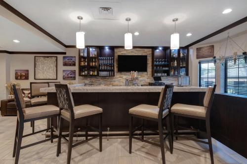 a kitchen with a bar with chairs and a tv at Staybridge Suites Tallahassee I-10 East by IHG in Tallahassee