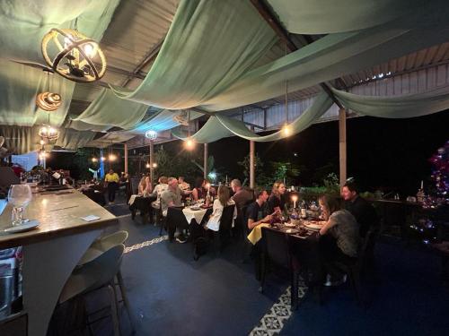 un grupo de personas sentadas en mesas en un restaurante en Ecolodge Kalaluna Resort en Drake