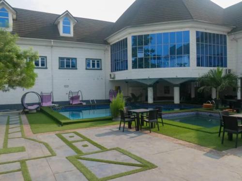 una casa con piscina, mesas y sillas en Hotel Belisco, en Owerri