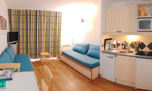 Ce petit appartement dispose d'un canapé bleu et d'une cuisine. dans l'établissement Studio Face Mer 3 Personnes, à Pornichet