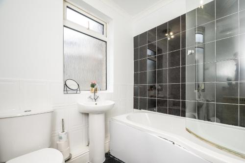 La salle de bains blanche est pourvue d'un lavabo, d'une baignoire et de toilettes. dans l'établissement The Mather Place, à Blackpool