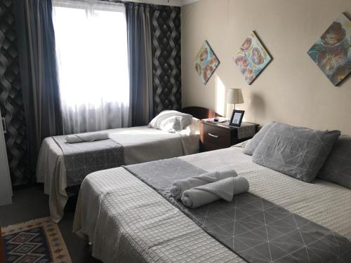 Habitación de hotel con 2 camas y ventana en Hotel Maquehue, en Concepción