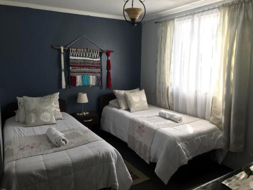 2 camas en un dormitorio con paredes azules en Hotel Maquehue, en Concepción