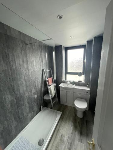 a bathroom with a tub and a toilet and a sink at Coastal home with lots of space 5 bedrooms. in Buckhaven