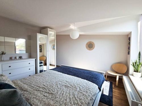 biała sypialnia z łóżkiem i komodą w obiekcie Oasis Oliwa w Gdańsku