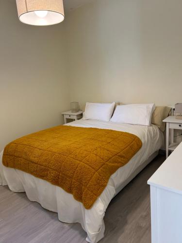 ein Schlafzimmer mit einem großen Bett mit einer braunen Decke in der Unterkunft Acogedor Bajo en Meira in Moaña