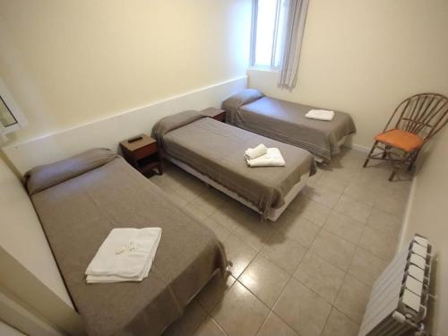 Cette petite chambre comprend deux lits et une chaise. dans l'établissement Carlos VII, à Mar del Plata