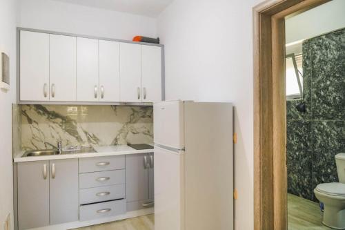 a kitchen with white cabinets and a white refrigerator at Villa Mateo in Shkalle Stenojt