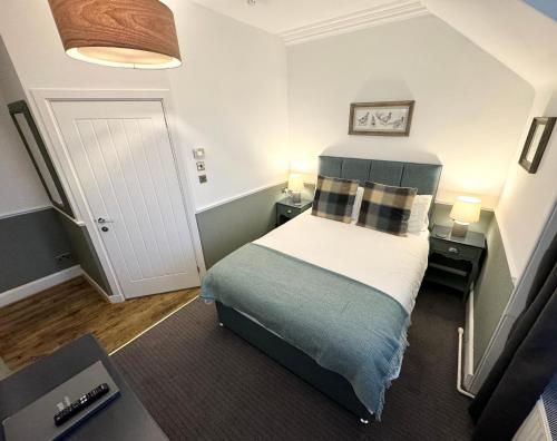 a small bedroom with a bed and two lamps at Ravenscraig Guest House in Aviemore