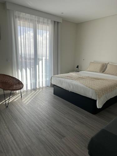 a bedroom with a bed and a chair and a window at Raphael Funchal Views Apartment in Funchal