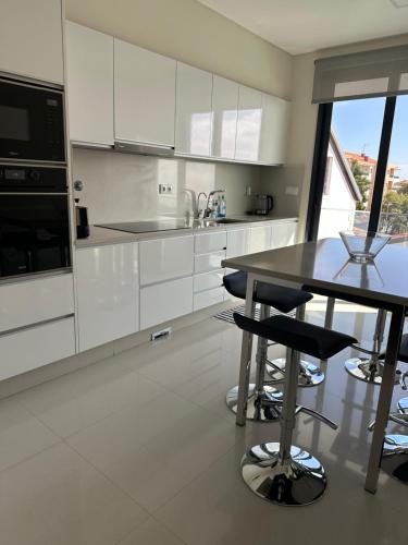 a kitchen with white cabinets and a table with stools at Raphael Funchal Views Apartment in Funchal