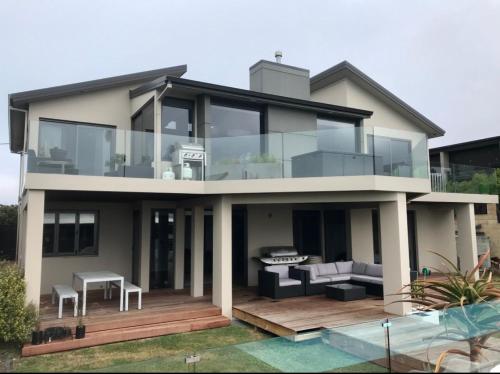 a large house with glass windows and a deck at Luxury 2 Bdrm Apt w Private Pool located on Scarborough Hill, Sumner. Christchurch in Christchurch