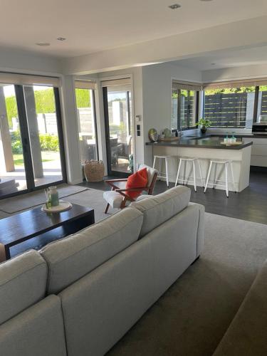 a living room with a couch and a kitchen at Luxury 2 Bdrm Ground Level Apt with Private Pool located on Scarborough Hill Sumner Christchurch in Christchurch