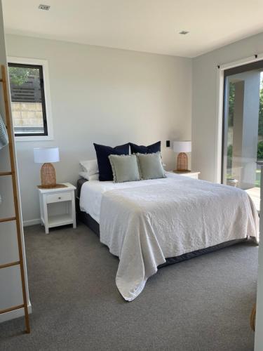 a white bedroom with a bed and two night stands at Luxury 2 Bdrm Apt w Private Pool located on Scarborough Hill, Sumner. Christchurch in Christchurch