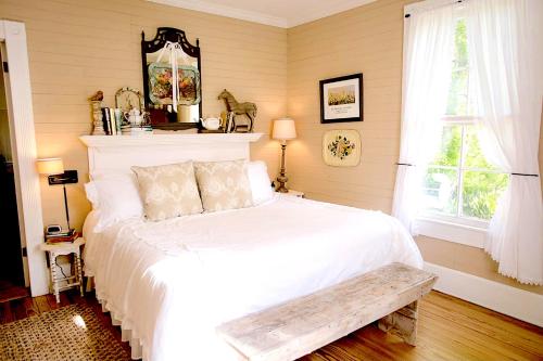 een slaapkamer met een wit bed met een bank erop bij Circa 1900 - Historic - Romantic - Private - Pond - Fenced Yard - The Cottage at Chappell Hill in Chappell Hill