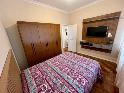 a bedroom with a bed and a flat screen tv at Apartamento Imperial no Centro de Petrópolis in Petrópolis