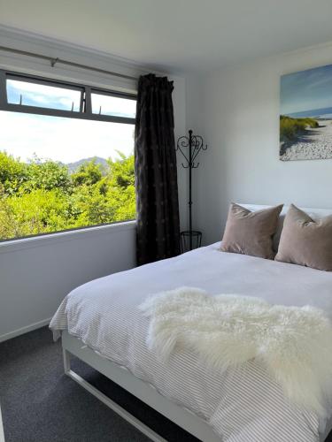 - une chambre avec un lit et une grande fenêtre dans l'établissement Mandhari - The View, à Whangamata
