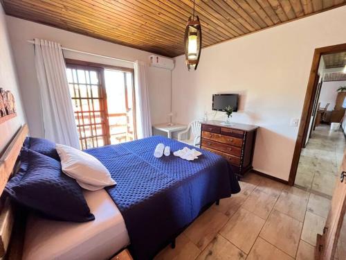 een slaapkamer met een blauw bed en een televisie bij Ap com Sacadas, 02 quartos e churrasqueira in Palhoça