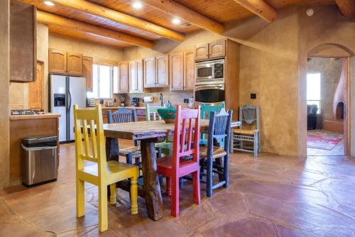 uma cozinha com cadeiras coloridas à volta de uma mesa de madeira em Balloon fiesta home em Albuquerque