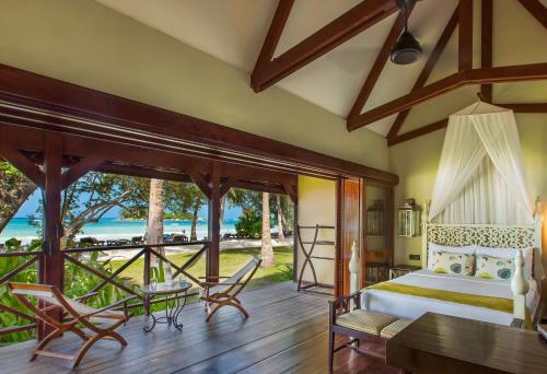 a bedroom with a bed and a view of the ocean at Paradise Sun Hotel Seychelles in Baie Sainte Anne